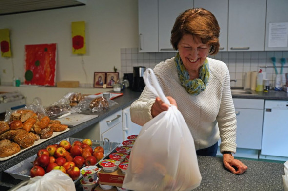 Nach dem Mittagessen in der Suppenküche verteilen Ehrenamtler wie Annemarie Bodenheim Tüten mit gespendeten Lebensmitteln.